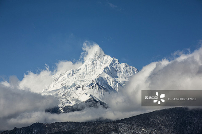 蓝天下云开雾散的梅里雪山主峰卡瓦格博峰创意图片