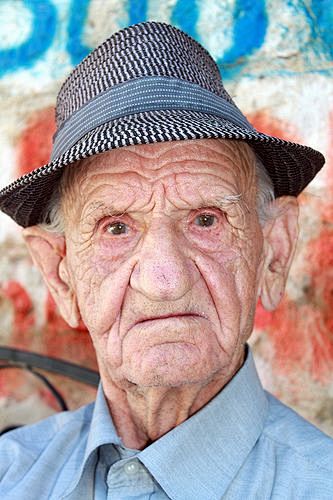 戴帽子的老人这个男人坐在阿尔巴尼亚杜雷西罗马露天剧场外面的树荫下