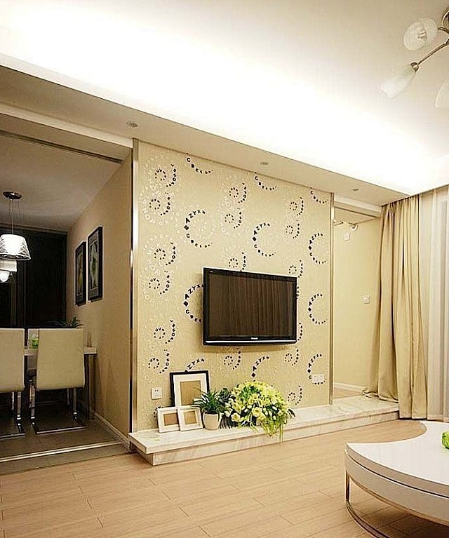 正面看客厅的电视背景墙暖黄色的壁纸装饰旁边是餐厅暖色调打造温馨