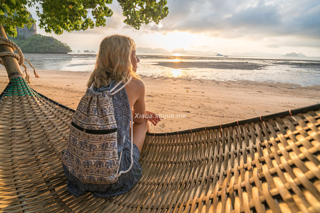 youngwomanwatchingsunrisefromhammockonthebeach