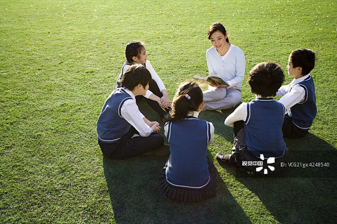 小学生在草地上围着老师学习