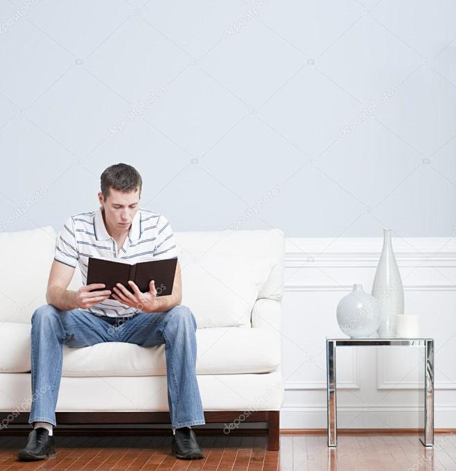 人坐在他的客厅里的白色沙发上阅读方形格式