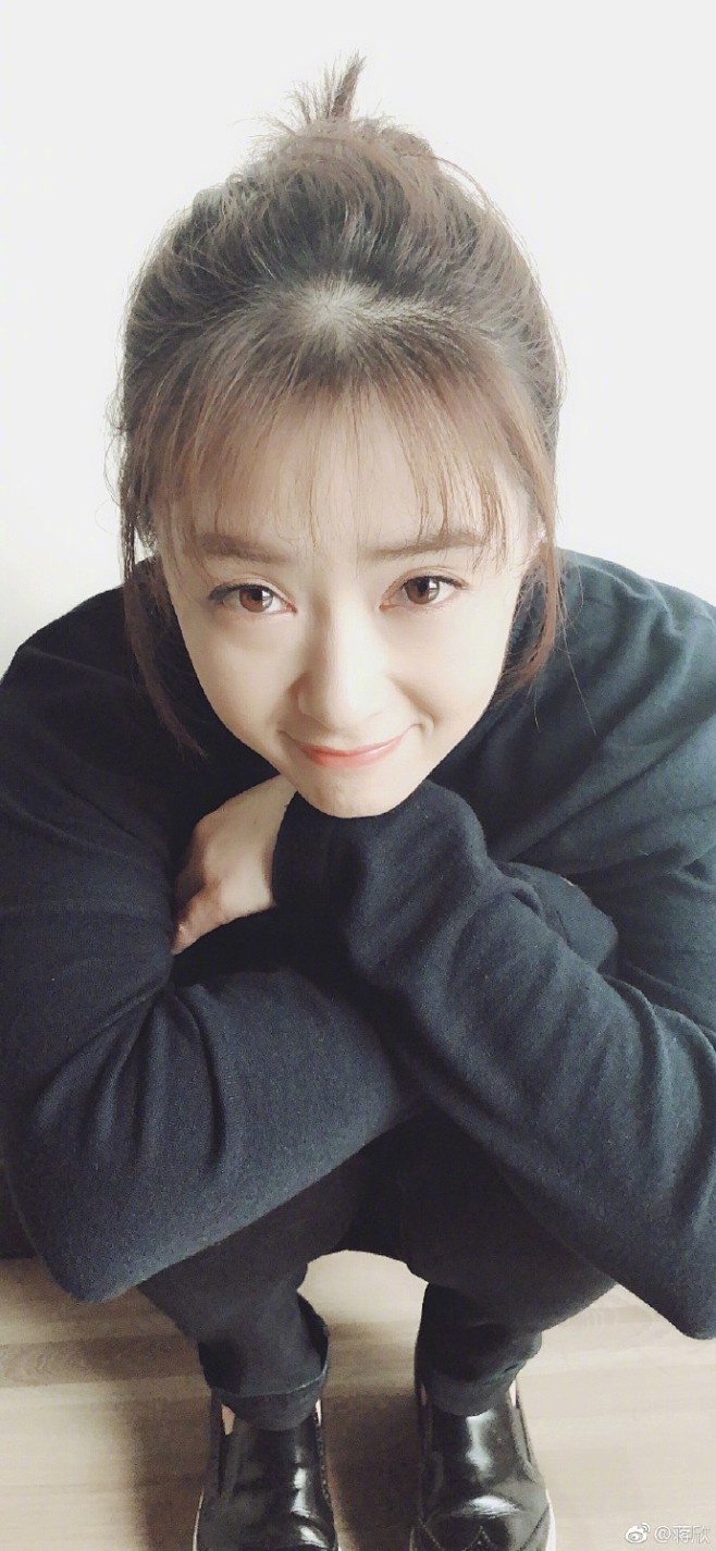 组图蒋欣穿黑衣盘发气质温柔双手捧脸蹲地露甜笑很俏皮照片中蒋欣穿着